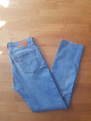Levi's 511 blåa jeans  - Klassiska ljusblå jeans från Levi's 511 med rak passform och femficksdesign. Jeansen har den ikoniska läderpatchen bak i midjan och röd Levi's-tagg på bakfickan. Tillverkade i slitstark denim, perfekta för en avslappnad och tidlös stil.
