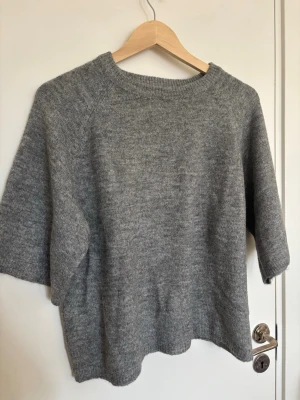 Grå stickad tröja med korta ärmar från lager 157 - En enkel och stilren grå stickad tröja med rund halsringning och korta ärmar, från lager 157.