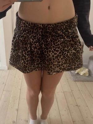 Leopardmönstrad kortkjol med resår - Säljer en snygg kortkjol med leopardmönster och bred resår i midjan. Kjolen har en avslappnad passform och är perfekt för dig som vill sticka ut. Materialet känns mjukt och följsamt mot huden.