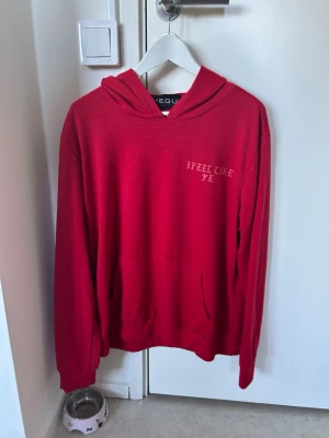Röd hoodie - Säljer en röd hoodie med texten 'I FEEL LIKE YE' på bröstet och 'FEEL LIKE PABLO' i stort tryck på ryggen. Hoodien har huva och en stor magficka. Perfekt för dig som gillar streetwear och vill sticka ut med Kanye West-inspirerad design.