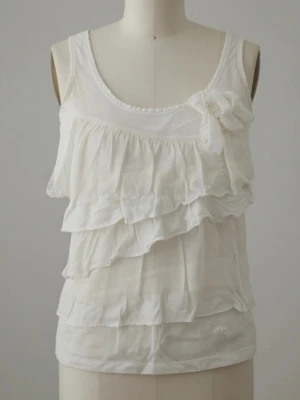 Vit ärmlös topp / linne med volanger och rosett. XS. Bomull. Lindex. - Vit ärmlös topp / linne med volanger och rosett. XS. Bomull. Lindex. Något missfärgad vid armhål men kan troligen tas bort med lite klorin.