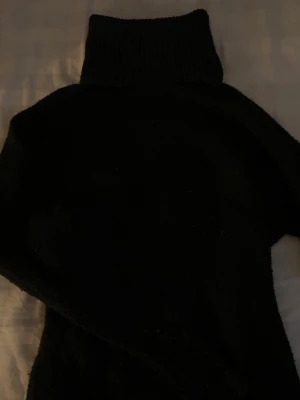 Svart polotröja i stickat material - Säljer en svart oversized stickad polotröja med hög krage och långa ärmar. 