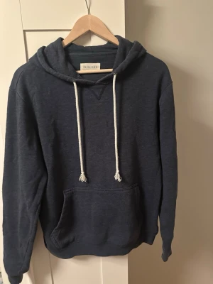 Mörkblå hoodie från Pier One - Tja säljer enMörkblå hoodie från Pier One med vita dragsnören. Perfekt för dig som gillar en enkel och stilren look.