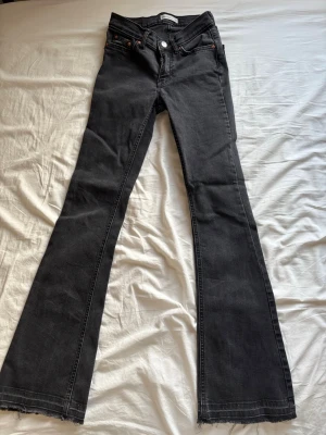 Svarta bootcut jeans med rå kant - Säljer ett par svarta bootcut jeans med uppsprät ner till. Jeansen har klassisk femficksmodell och hög midja. Snygg tvätt och stretchigt material som sitter skönt. 