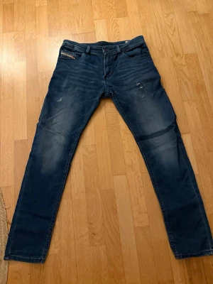 Blå slim skinny jeans från Diesel - Säljer ett par blå slim skinny jeans från Diesel, modell Thommer-J JJJ. Jeansen har klassisk femficksdesign, lätt slitna detaljer och stretchigt material för extra komfort. Perfekta för dig som gillar en smal passform och modern look.