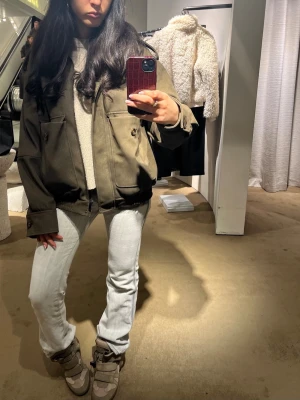 Olivgrön bomberjacka med fickor - Säljer en olivgrön bomberjacka med stora fickor och knappar framtill. Jackan har en loose passform och är långärmad, med päls runt halsen. (syns inte så bra på bild). Sjuuuukt snygg och cool jacka men har alldeles för många. Fint fint skick. Ord pris 900. Perfekt nu till våren / sommarkvällar.