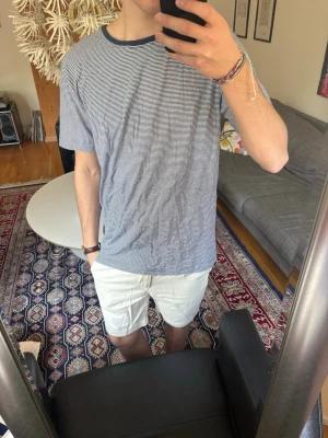 Randig t-shirt  - Fortfarande med taggen på (nypris 490). Snygg t-shirt med tunna horisontella ränder i vitt och mörkblått. T-shirten har en mörkblå rund halsringning och korta ärmar. 