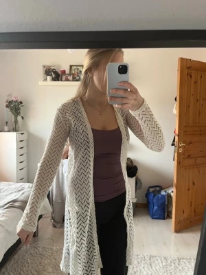 Vit lång spetskofta med mönster - Säljer en vit lång kofta i spets med ”hålmönster”. Koftan har långa ärmar och är öppen framtill. I storlek 158-164 men passar även Xs/S