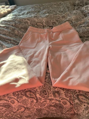 Ljusrosa mjukisbyxor med fickor - Säljer ett par ljusrosa mjukisbyxor med bred resår i midjan och dragsko. Byxorna har två stora fickor framtill och är gjorda i ett mjukt, tjockt bomullstyg. Perfekta för chill dagar hemma eller när du vill vara extra bekväm. Helt nya och prislapp finns kvar nypris:200kr storlek:Xl
