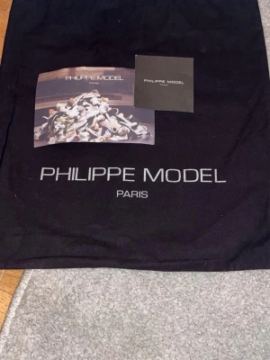 Philippe Model blå sneakers - Snygga sneakers från Philippe Model i mörkblått läder och mocka med grå detaljer. Klassisk låg modell med vita och svarta sulor samt matchande blå skosnören. Perfekta för dig som gillar stilrena och exklusiva sneakers med fransk design.