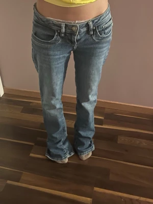 Blå bootcut jeans från LTB - Säljer ett par blå bootcut jeans från LTB, modell Valerie. Jeansen har låg midja, klassiska fem fickor och dragkedjegylf. Snygg tvättad denim med lätt slitning och raka ben som går ut lite nedtill. Midjan platt - 35cm, innerbens längden - 80cm Långa på mig som är 155cm Väldigt bra skick. Lite slitna längst ner men syns knappt. Kolla in min profil för fler trendiga plagg. 