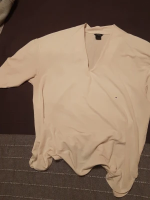 Beige v-ringad topp från Lindex - Snygg beige topp från Lindex med v-ringning och lång ärm. Enkel och stilren design som passar till många olika outfits. Mjuk och skön känsla i materialet, perfekt för dig som gillar en clean look.