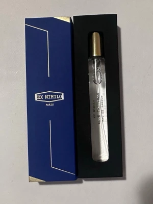 Ex Nihilo Blue Talisman  - Lyxig parfym från Ex Nihilo, Bleu Talisman Eau de Parfum. Kommer i en elegant smal glasflaska med guldfärgat lock och stilren blå ask med vita och guldiga detaljer. Perfekt för dig som gillar exklusiva dofter och snygg design. Oanvänd 