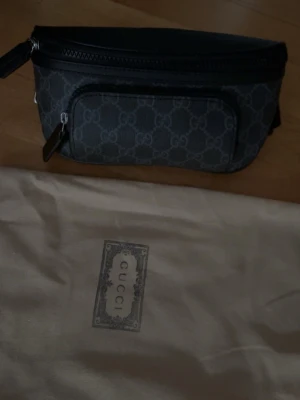 Svart Gucci Magväska - Säljer en svart axel/midje/magväska från Gucci med monogram. Man kan justera hur den ska sitta. riktigt snygg och kommer med vanlig dustbag