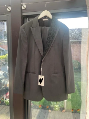 Grå kavaj från Zara - Snygg grå kavaj från Zara med unik svart mönstrad  Klassisk passform med tre fickor framtill och elegant snitt. Perfekt för dig som vill sticka ut med stilren design och exklusiva detaljer.