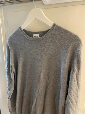 Grå tröja  - Enkel och stilren grå tröja från Zara med rund halsringning och långa ärmar. Perfekt för lager-på-lager och passar till det mesta. Mjuk och skön känsla i materialet.