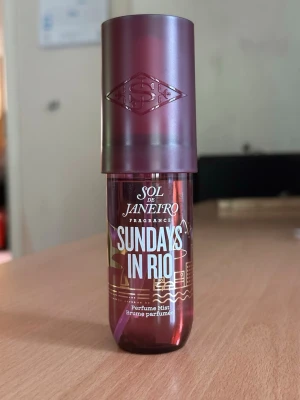 Sol de Janeiro Sundays in Rio parfym - Parfymmist från Sol de Janeiro med namnet Sundays in Rio. Flaskan är cylinderformad i mörklila plast med vit text och guldiga detaljer. Praktisk sprayfunktion och matchande lila lock med logotyp. Perfekt att ha med i väskan för en fräsch doft.