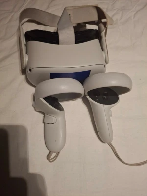 Oculus Meta Quest 2 VR-headset - Säljer ett Oculus Quest 2 VR-headset i vitt med tillhörande två handkontroller. Headsetet har justerbart band. Perfekt för dig som vill uppleva VR-spel på riktigt. Fungerar perfekt utan några fel!