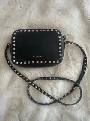 Valentino camera bag  - Säljer nu min superfina valentino camera bag med guldiga nitar. Den är i fint skick men har lite små defekter på utsidan som knappt syns. Små fläckar på insidan och en av nitarna är utbytta till en annan likadan valentino nit som är likadan och äkta, det syns bättre på sista bilden. Ingenting medföljer till väskan för det har jag tyvärr inte kvar längre. Skriv till mig för frågor☺️🌸