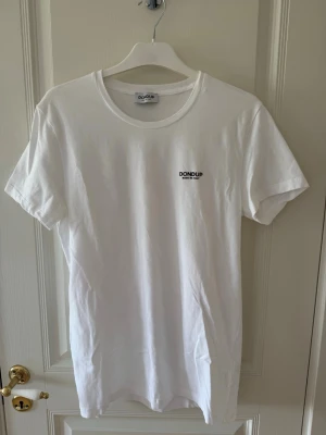 Vit Dondup T-shirt - En skön och stilren T-shirt från Dondup med märket på bröstet. Storlek Large men passar mer som en Medium, lite slimmad vid axlarna.  Endast använd ett fåtal gånger, som ny