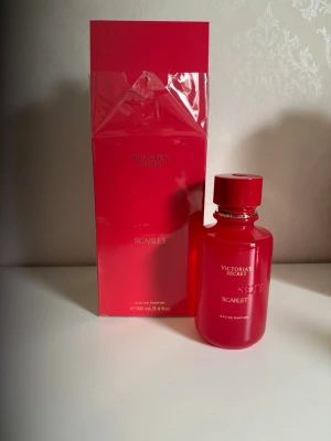 Victoria's Secret Scarlet parfym 100ml  - Victoria's Secret Scarlet Eau de Parfum i en snygg röd glasflaska med matchande röd kartong. Doften har inslag av rosblad, jasmin sambac och silkeslen ambrette. Perfekt för dig som gillar blommiga och sensuella parfymer.