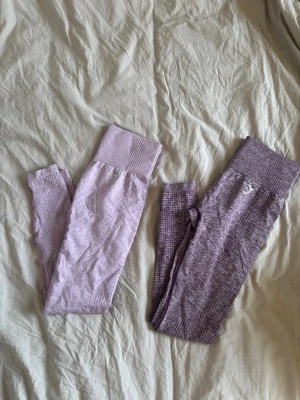 Lila tights från Gymshark - Två träningstights från Gymshark. Materialet är stretchigt och bekvämt, perfekt för träning eller gym. De ljusa tightsen är i xs och de mörkare är i xs eller s