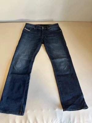 Mörkblå straight jeans från Diesel - Snygga mörkblå jeans från Diesel med klassisk rak passform och fem fickor. Perfekta för en stilren och avslappnad look.