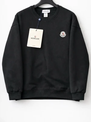 Svart sweatshirt från Moncler - Stilren svart sweatshirt från Moncler med rund halsringning och ribbade muddar. Tröjan har en liten Moncler-logga broderad på bröstet och är tillverkad i mjukt bomullsmaterial. Perfekt för en clean och avslappnad look.