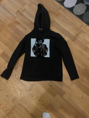 Svart limitato  - Cool svart hoodie med jimmi henrix. Hoodien har snören med metalländar och långa ärmar. Perfekt för dig som gillar musik och streetstyle.