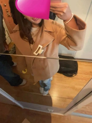 Beige skepparkavaj med bred krage - Snygg beige skepparkavaj med dubbelknäppning och bred krage. Jackan har raka ärmar och två sidofickor. Perfekt för dig som gillar klassiska och stilrena plagg.