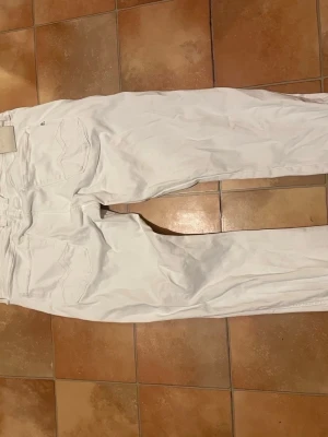 Vita raka jeans från Reply - Säljer ett par vita jeans från Reply med rak passform och klassiska fem fickor. Jeansen har mellan midja och tydliga sömmar på bakfickorna. Perfekta för en clean och fräsch look. Materialet är bomull för skön känsla. Pris kan diskuteras vid snabb affär 