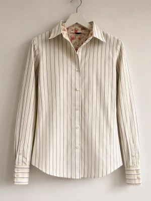 Randig skjorta med blommigt foder - Klassisk vit skjorta med tunna svarta och blå ränder samt blommigt foder i kragen. Skjortan har långa ärmar, knäppning framtill och breda manschetter med dubbla knappar. Tillverkad i bomull för en skön känsla och stilren look.