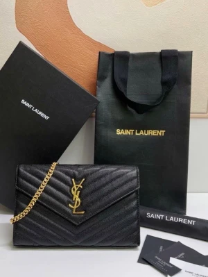 Svart Saint Laurent handväska i läder - Snygg svart handväska från Saint Laurent i quiltat läder med guldfärgad kedja och ikonisk YSL-logga framtill. Väskan har ett elegant kuvertformat lock och stilren design som passar till många looks. Perfekt accessoar för dig som gillar lyxiga detaljer.