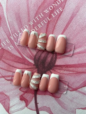 Press-on naglar rosa fransk design - Snygga press-on naglar i rosa med vit fransk tipp. Några naglar har dekorativa pärlor och en liten silverstjärna för extra detalj. Formen är rundad och naglarna har en glansig finish. Perfekt för dig som vill ha en trendig och elegant look.