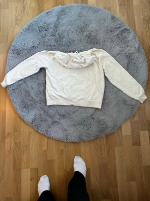 Vit hoodie med huva och ficka - Säljer en enkel och stilren vit hoodie med huva och dragsko. Hoodien har en klassisk känguruficka framtill och långa ärmar. Perfekt för dig som gillar en clean och avslappnad look. Materialet känns mjukt och bekvämt mot huden.