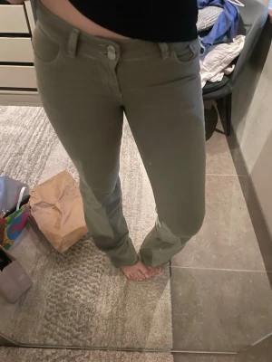 Olivgröna bootcut jeans - Snygga olivgröna jeans med bootcut passform och klassiska fem fickor. Jeansen har dekorativa sömmar på bakfickorna och stängs med knapp och dragkedja. Perfekta för en avslappnad och trendig look. Virala Nelly jeansen aldrig använda då de ientligen inte är min stil