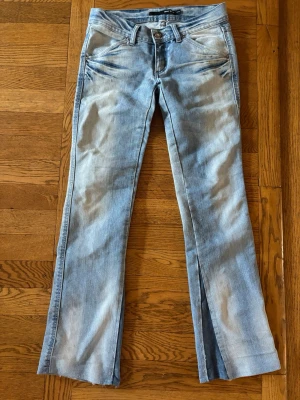 Ljusblå bootcut jeans  - Jättefina jeans med coola detaljer nertill samt bakfickorna! Midjemåttet är 36cm och innerbenslängden är 74cm.