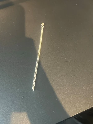 Silverfärgat kedjearmband - Stilrent armband i silverfärg med klassisk kedjedesign och karbinlås. Perfekt för dig som gillar minimalistiska accessoarer med en clean look. Materialet ser ut att vara metall och armbandet har en enkel men snygg form.