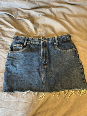 Mörkblå jeanskjol med fransig kant - Högmidjad mörkblå jeanskjol, fransig ner till