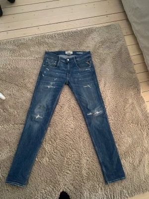 Blå slim fit jeans från Replay - Blå jeans från Replay med schyssta slitningar.