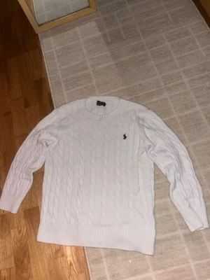 Vit kabelstickad tröja från Polo Ralph Lauren - Ralph Lauren sweatshirt storlek S skit snygg rekommenderar pris kan diskuteras. Lappen inne i tröjan på bild 2 är sönder men hänger fof men annars är tröjan ny och äkta och super bra skick!
