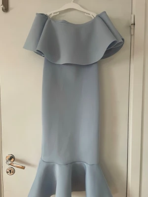 Ljusblå klänning från Missguided - Superfin ljusblå långklänning från Missguided med volangdetalj upptill samt vid fållen. Man kan både ha den offsholder eller ta upp axlarna. Kan användas som balklänning men också som en festklänning🩵