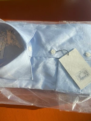Ljusblå skjorta från These Glory Days - Klassisk ljusblå skjorta från These Glory Days i bomull. Skjortan har en stilren design med knappar framtill och en snygg krage. Perfekt för dig som gillar en clean och enkel look. Storlek xs men killen på bild 3 är 179 så stor i storleken! Skjortan som skickas är fortfarande i plasten nypris:1099kr