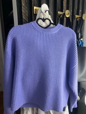 Ljuslila stickad tröja - En oversized, ribbstickad tröja i ljuslila med rund halsringning och långa ärmar. Tröjan har en avslappnad passform och är tillverkad i ett mjukt, tjockt material som passar perfekt för kyligare dagar.