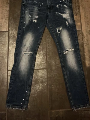 Supply and demand jeans  - Säljer ett mörkblåa par jeans med slitningar. Jeansen har en slim fit och coolt tvättad look med ljusare partier på låren. Bra skick. 