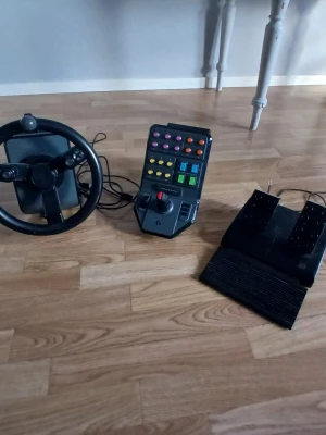 Logitech ratt, pedaler och kontrollpanel - Säljer ett set med ratt, pedaler och kontrollpanel från Logitech. Perfekt för dig som gillar racingspel eller simulatorer. Ratten är svart med flera knappar, pedalerna är också svarta och kontrollpanelen har många färgglada knappar och en joystick. Allt kopplas ihop med sladd. Måste hämtas i Mönsterås 