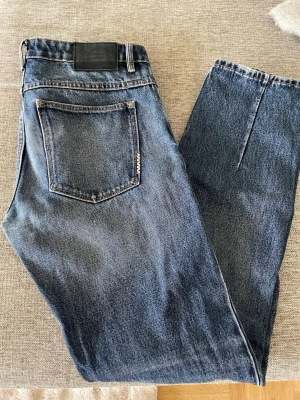 Blå raka jeans från Neuw - Snygga blå jeans från Neuw med klassisk femficksmodell och raka ben. Jeansen har en mörk tvätt och är gjorda i slitstark denim. Perfekta för en avslappnad och trendig stil. Storlek32/34. Ny pris: 699kr, mitt pris 349kr
