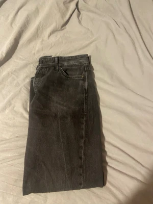 Svarta raka jeans w31 l32 - Säljer ett par svarta raka jeans med klassisk femficksmodell och bälteshällor. Jeansen har en enkel och stilren look, perfekta till en avslappnad outfit. Materialet är denim i bomull och färgen är tvättad svart.