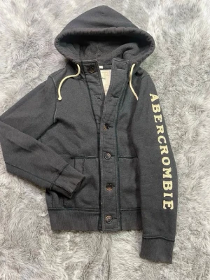 Abercombrie&Fitch Hoodie - Säljer denna sällsynta och mycket eftertraktade Abercrombie & Fitch hoodie | Storlek M | Mycket bra skick, saknas dock en knapp näst högst upp, men ger tröjan en lite unikare design | Vid eventuella frågor hör gärna av dig och erbjuder bra pris vid köp av bundle 😁✅