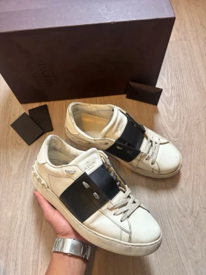 Valentino skor svarta - Tja, säljer ett par svarta och vita sneakers från valentino. Storlek: 40,5 fast med en stor passform. De har använts sparsamt men det har ändå blivit att det lossnat lite stygn framme vid tårna (tydligare bild kan skickas) och att färgen innuti även börjar lossna. Vilket händer för valentino skor genom tiden. Tveka inte på att slänga iväg ett prisförslag eller på att fråga något som du undrar! Mvh Valentino